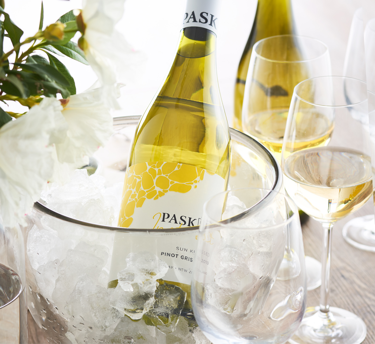 Pask Sun King Pinot Gris chilling in an ice bucket alongside wine glasses and white flowers