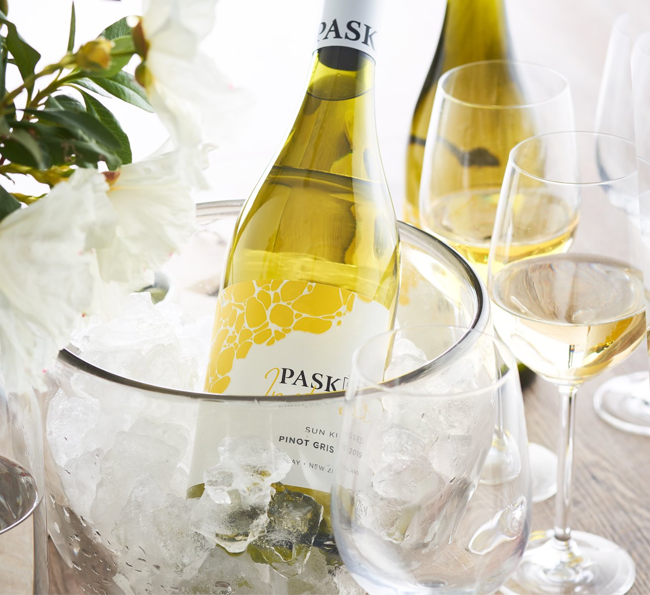 Pask Sun Kissed Pinot Gris chilling in an ice bucket alongside wine glasses and white flowers