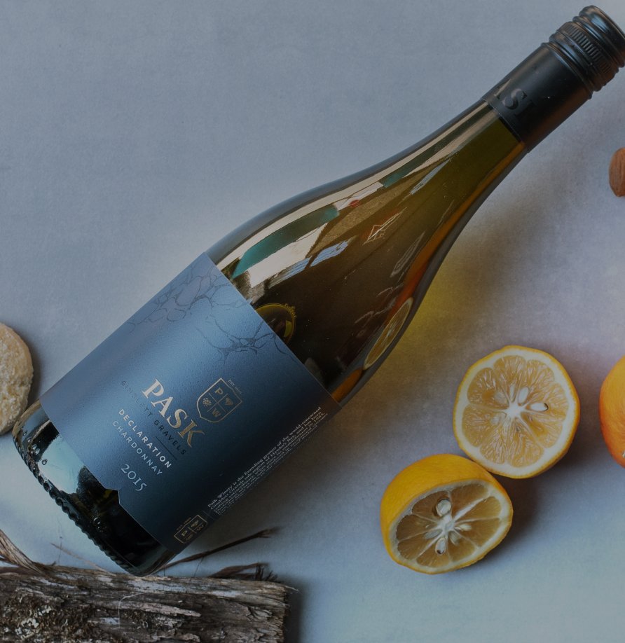 Pask Declaration Chardonnay 2015 bottle lying on its side beside sliced lemons on a light surface