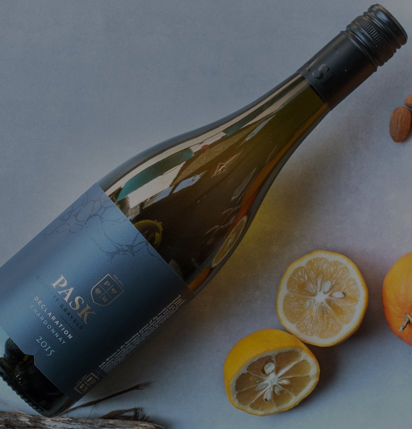 Pask Declaration Chardonnay 2015 bottle lying on its side beside halved lemons and almonds